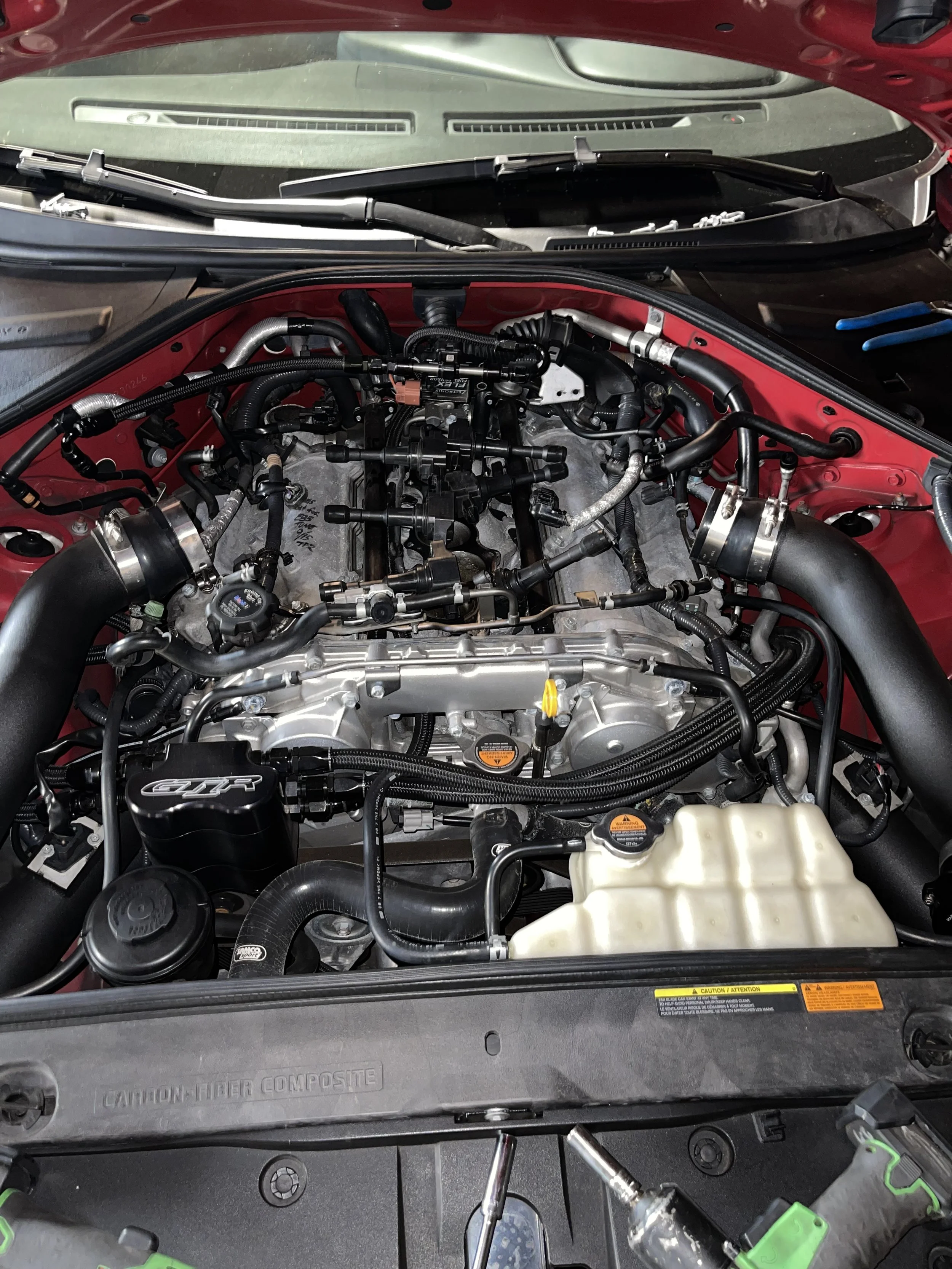 Car engine with various hoses, pipes, and components visible under the hood.