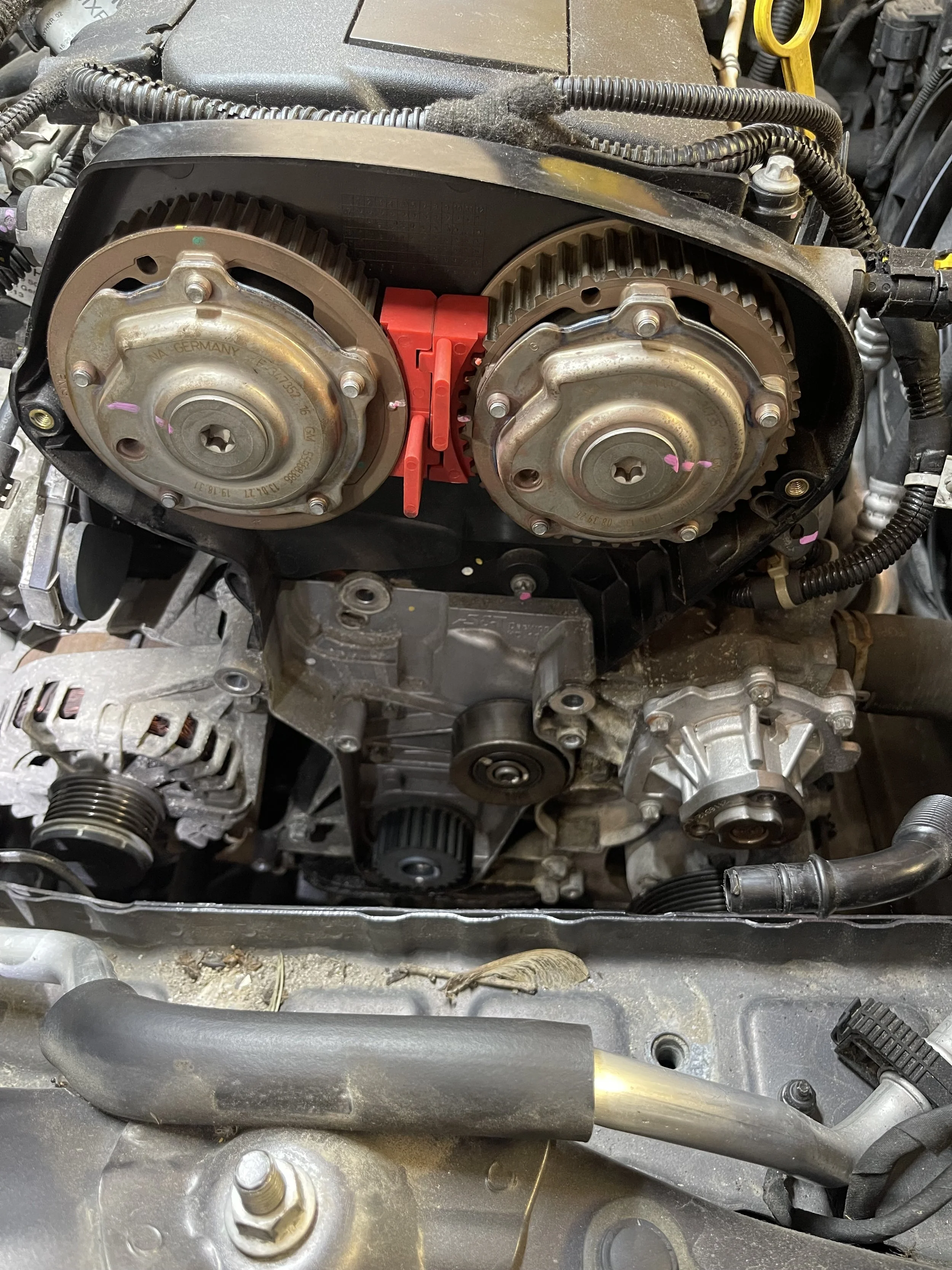 Engine with timing components and drive belts visible, part of a vehicle's engine bay.
