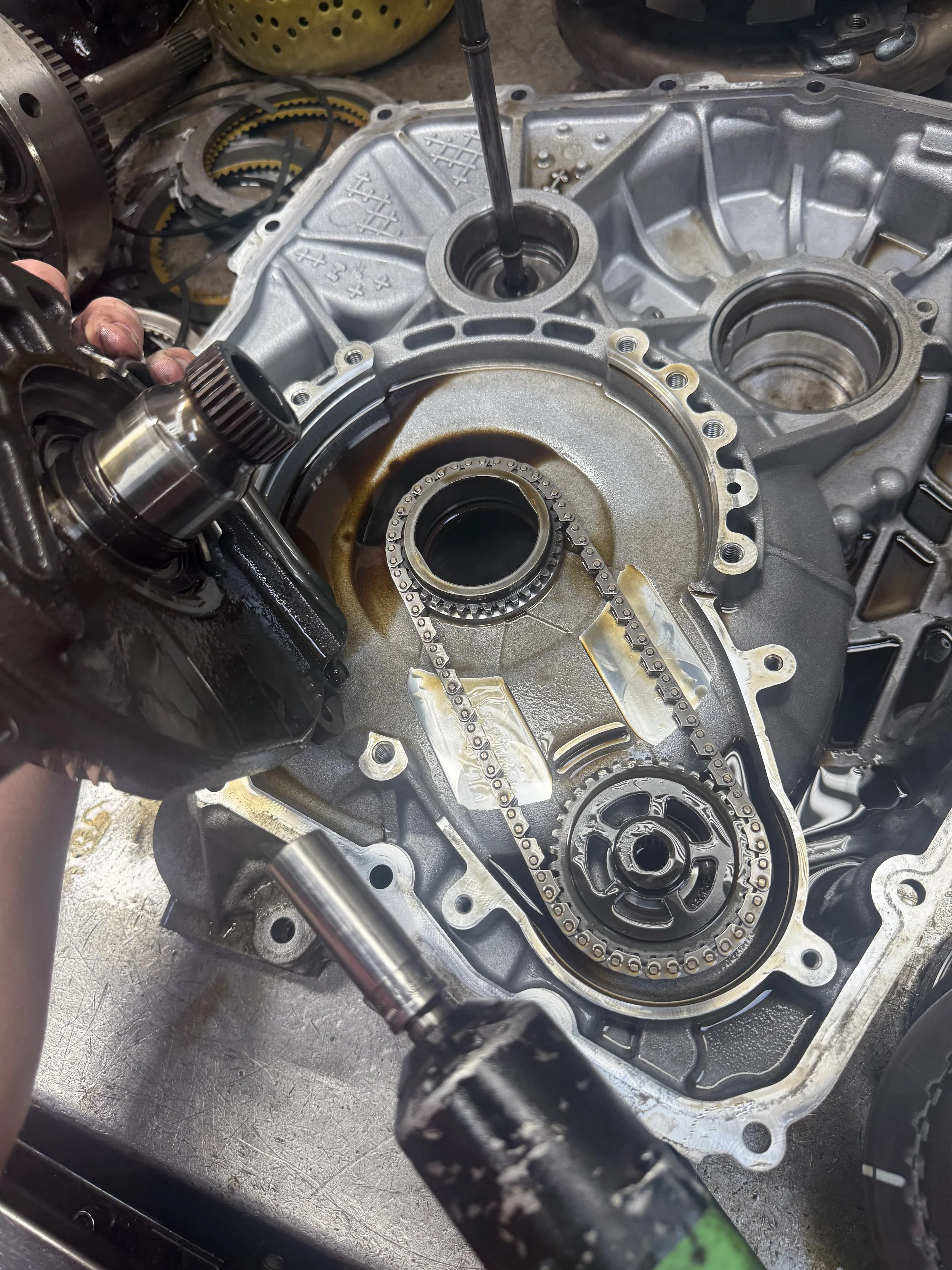 Inside an engine case with the timing chain being installed; tools and engine parts are visible.