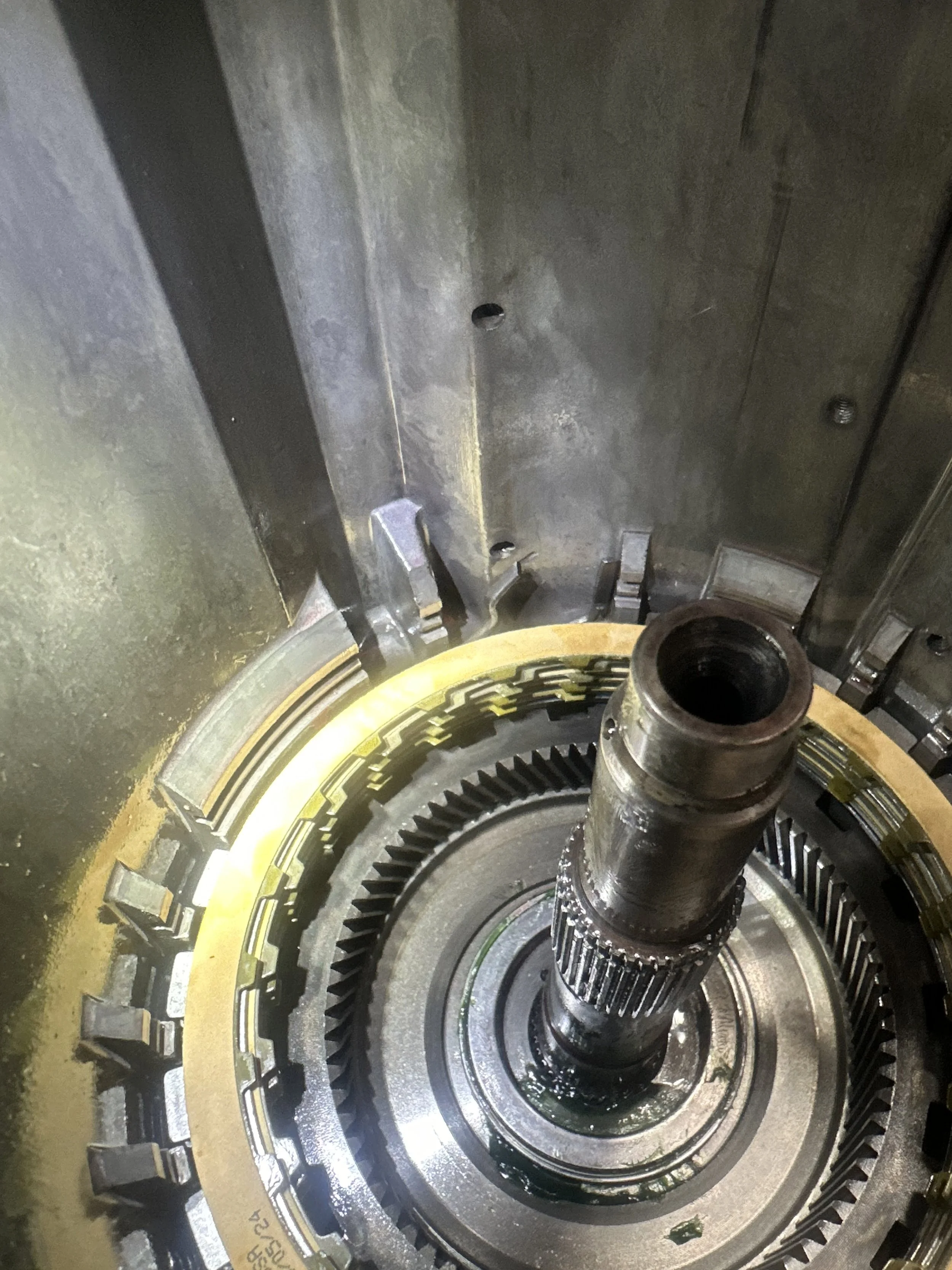 Close-up view of a large mechanical gear assembly inside an industrial machine, with visible metal gears and shaft.