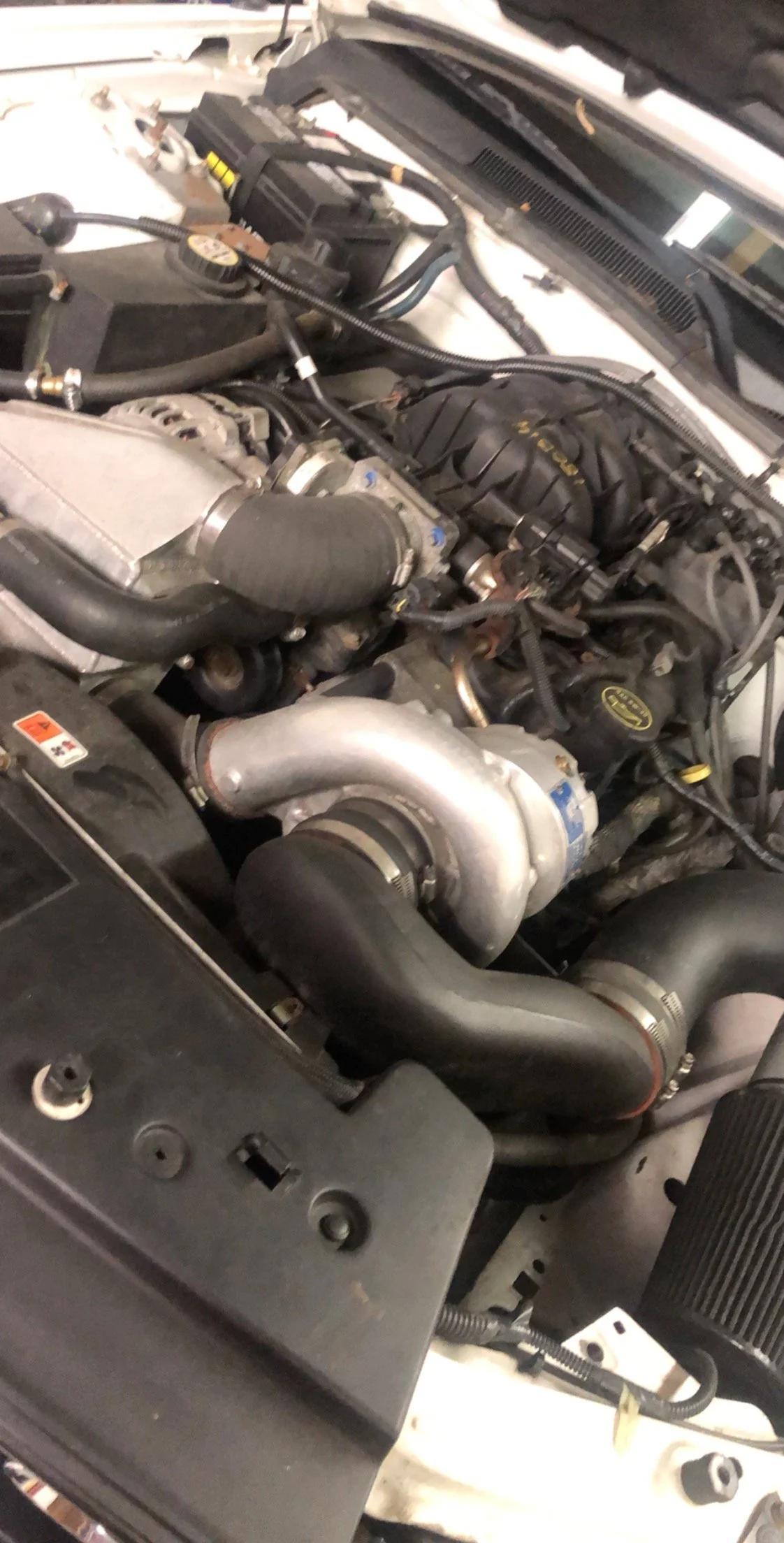 Close-up view of a car engine with various hoses, pipes, and components.