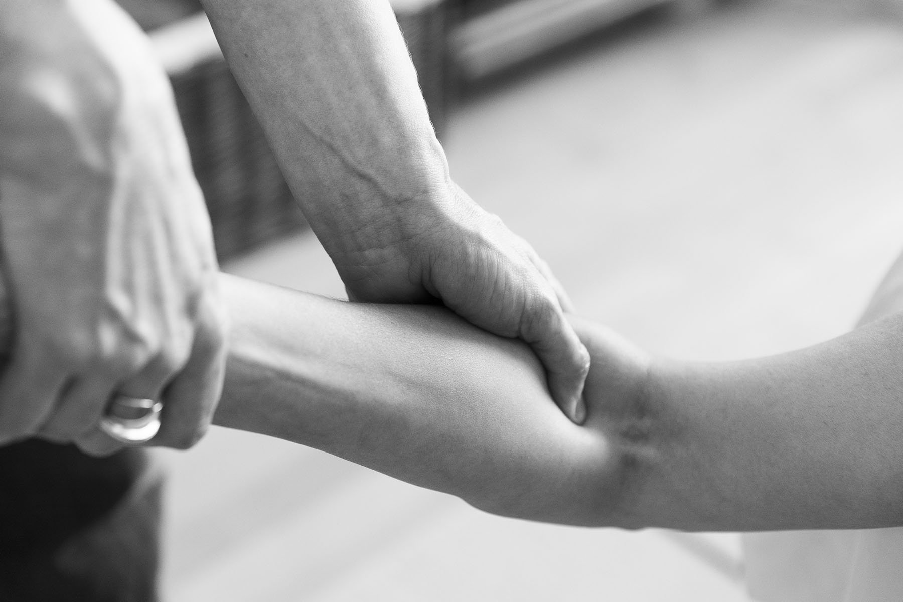 Hånd der udfører en terapeutisk behandling på en persons arm.