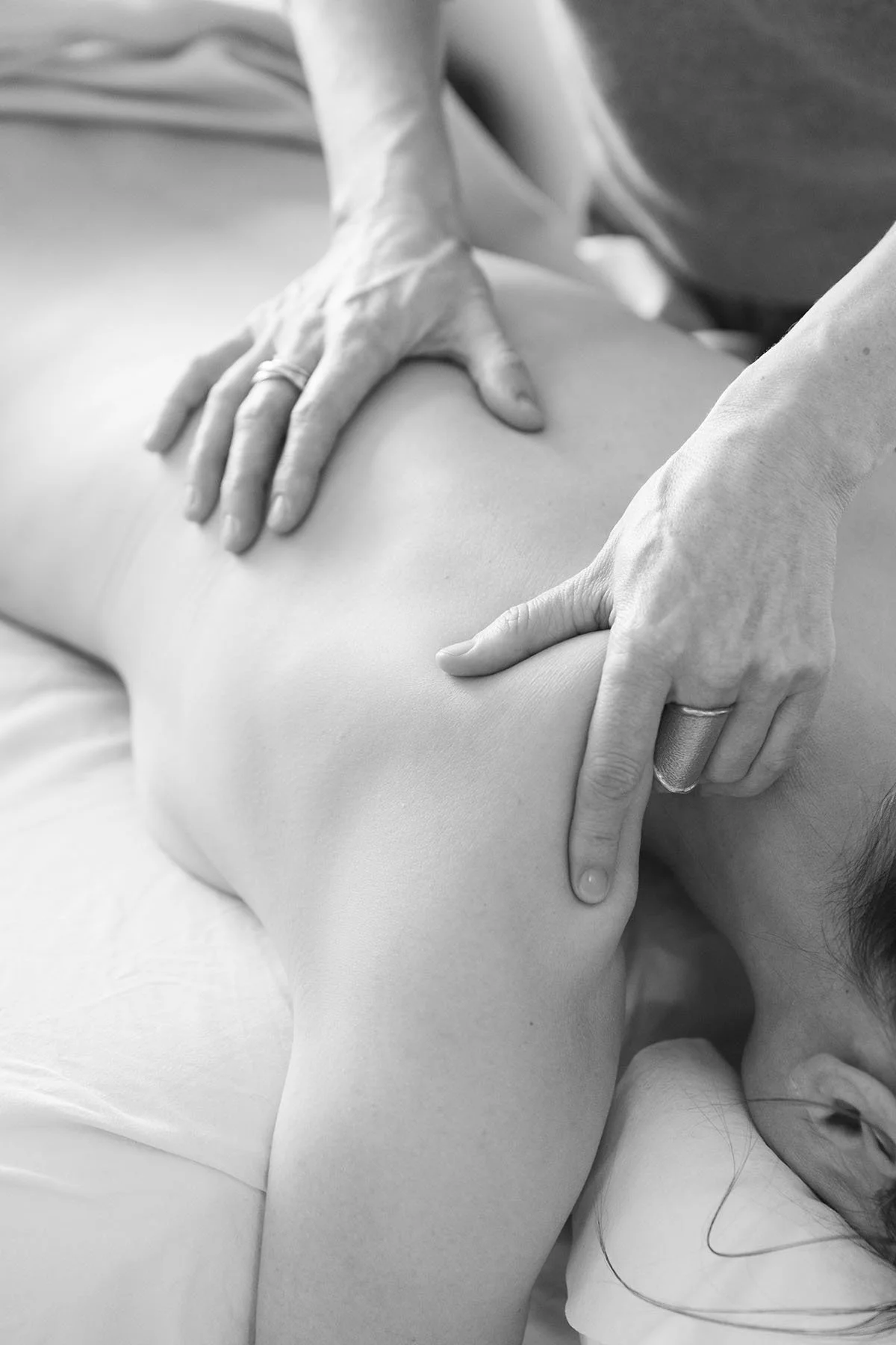 Sort-hvid billede af en person, der får en massage på skulderen af en massør.