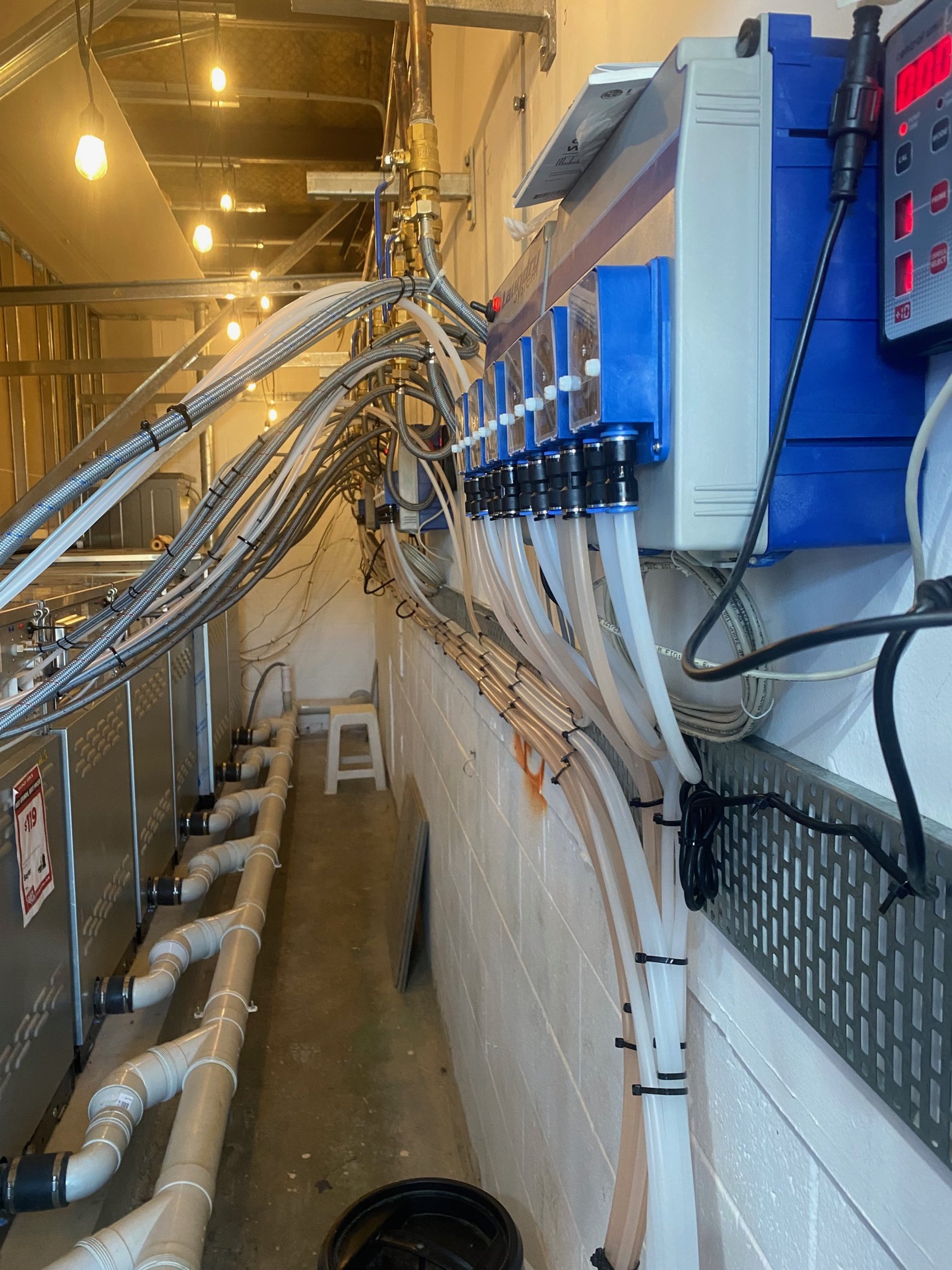 A utility or server room with multiple electrical boxes, conduit pipes, and wires running overhead and along the wall.