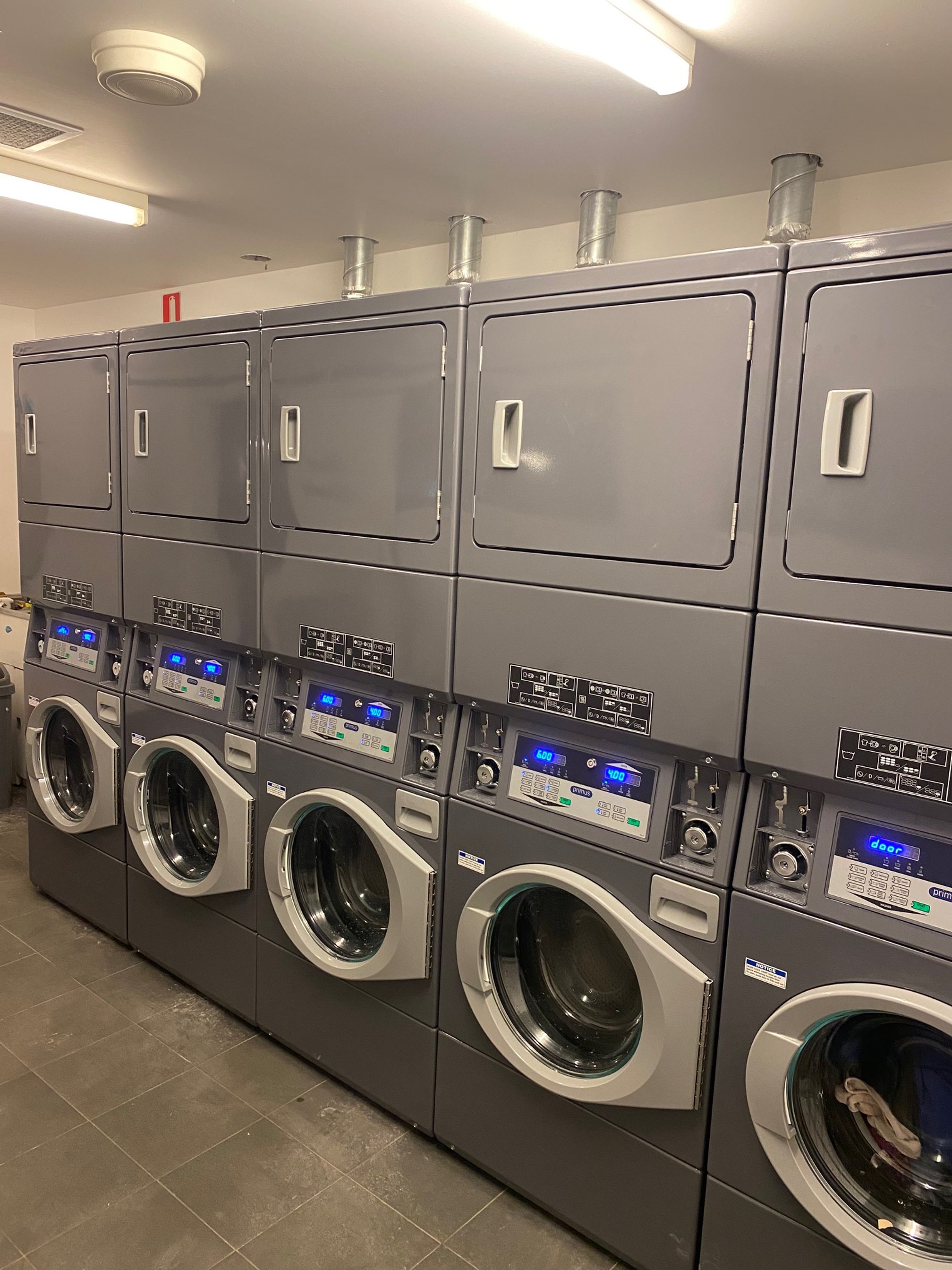 Row of commercial washing machines in a laundry room.