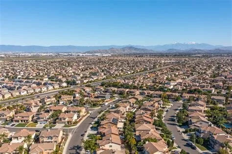 A view of a suburban neighborhood with houses, winding streets, and mountains in the background under a clear blue sky.