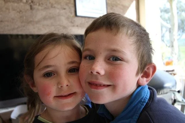 A young girl and boy, their cheeks smooshed together smiling for a photo