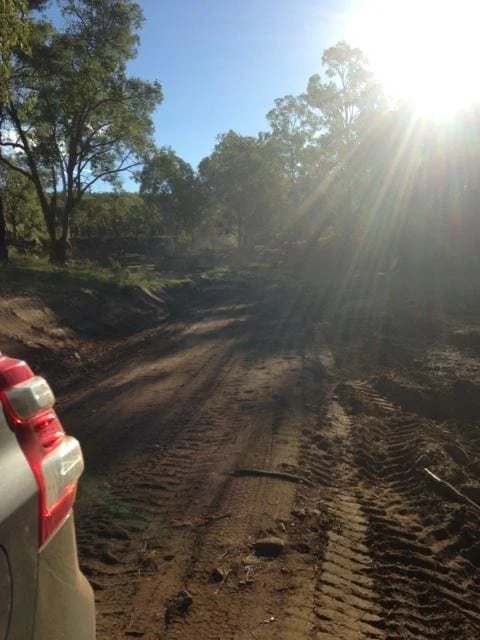 A dirt road with tyre tracks getting hit by the sun