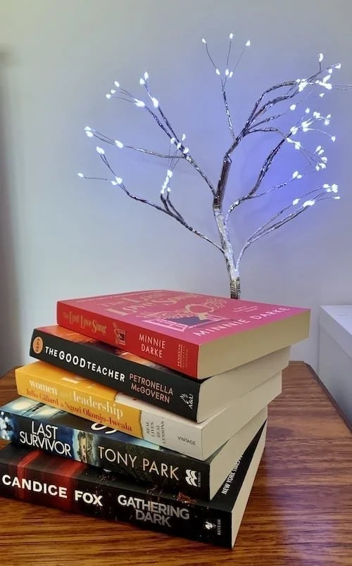 A stack of books in front of a lit up branch