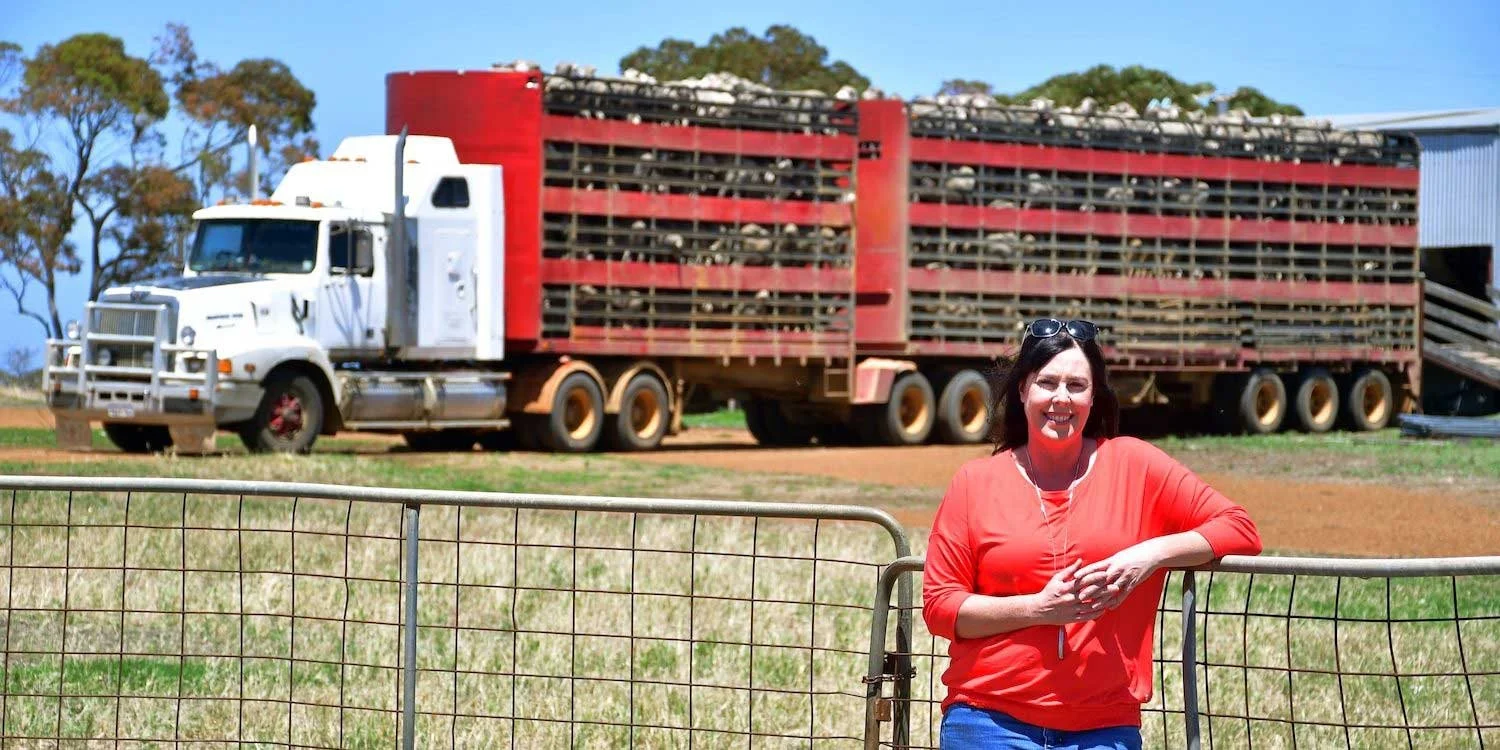 Fleur stands in front of a huge truck with loads of sheep on the back