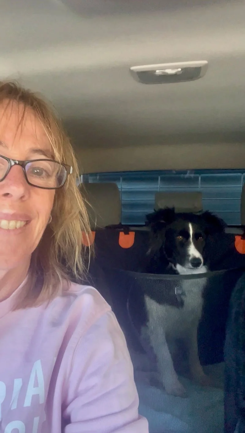 Fleur smiles from the front seat of her car, in the back Shadow is sitting in the back, ready to go!