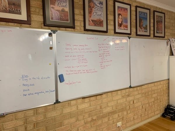 Three whiteboards in a row, two have much writing on them. Plotting out things in different colours