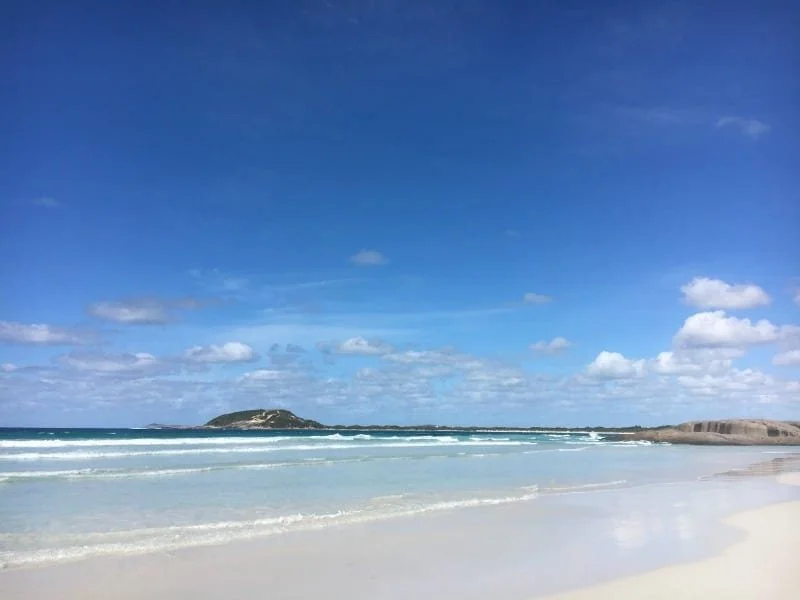 A beach. Beautiful white sand, a blue ocean meeting a blue sky