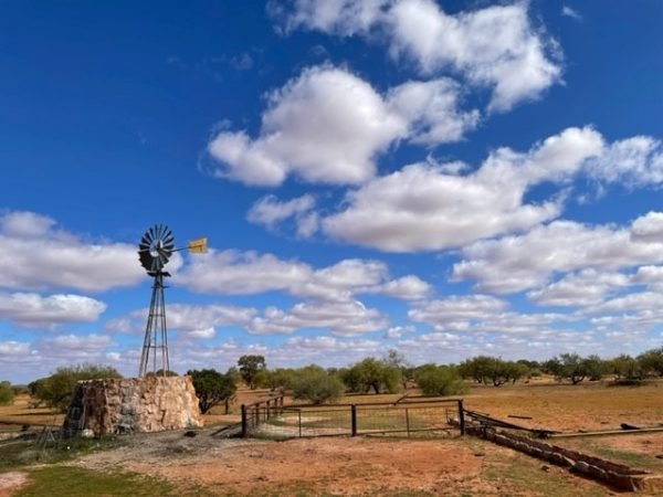 A windmill sits with the blue sky as a background