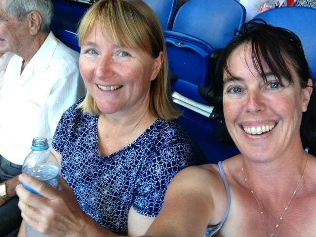 Two women smiling at the camera sitting in plastic seats