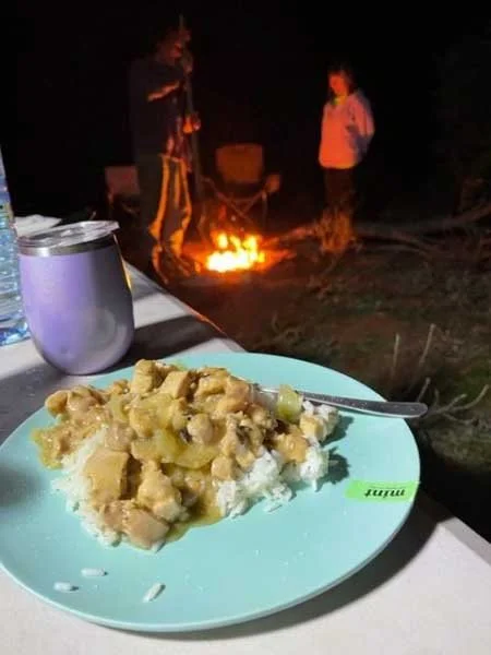 Apricot Chicken on a plate, the campfire behind