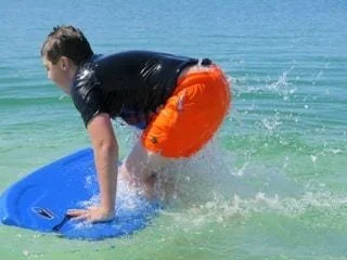 A young boy on a boogie board in the water