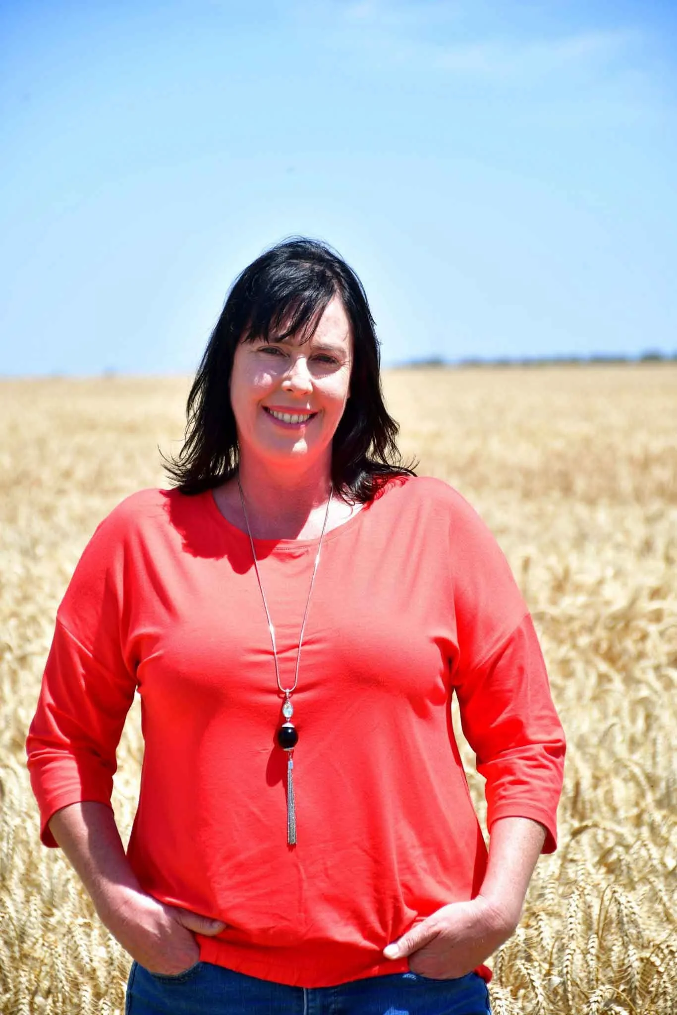 Fleur stands smiling out on the farm.