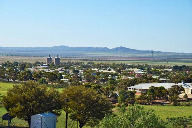 A small town with two big silos in the distance