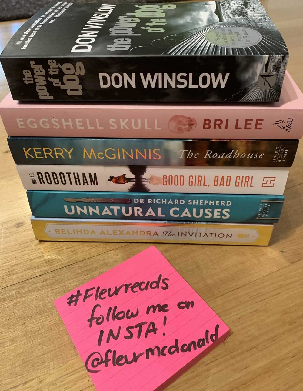 A stack of 6 books sits on a desk next to a postit note that says: #Fleurreads follow me on insta! @fleurmcdonald