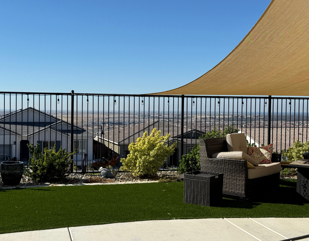 Rooftop patio with outdoor seating and views of a suburban neighborhood and distant cityscape under a clear blue sky.