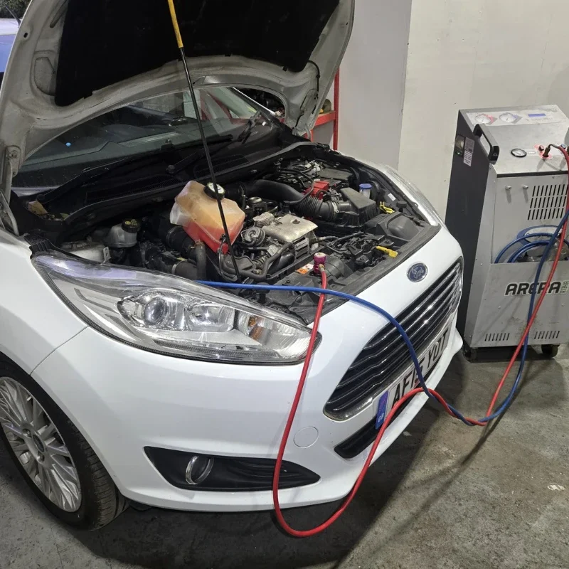 Car undergoing air conditioning service in a garage