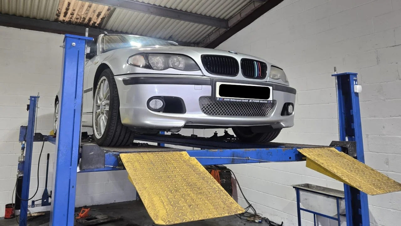 A BMW on a ramp at Premier Tyres Spondon in Derby, having a clutch and dual mass flywheel replacement with the underside of the vehicle exposed.