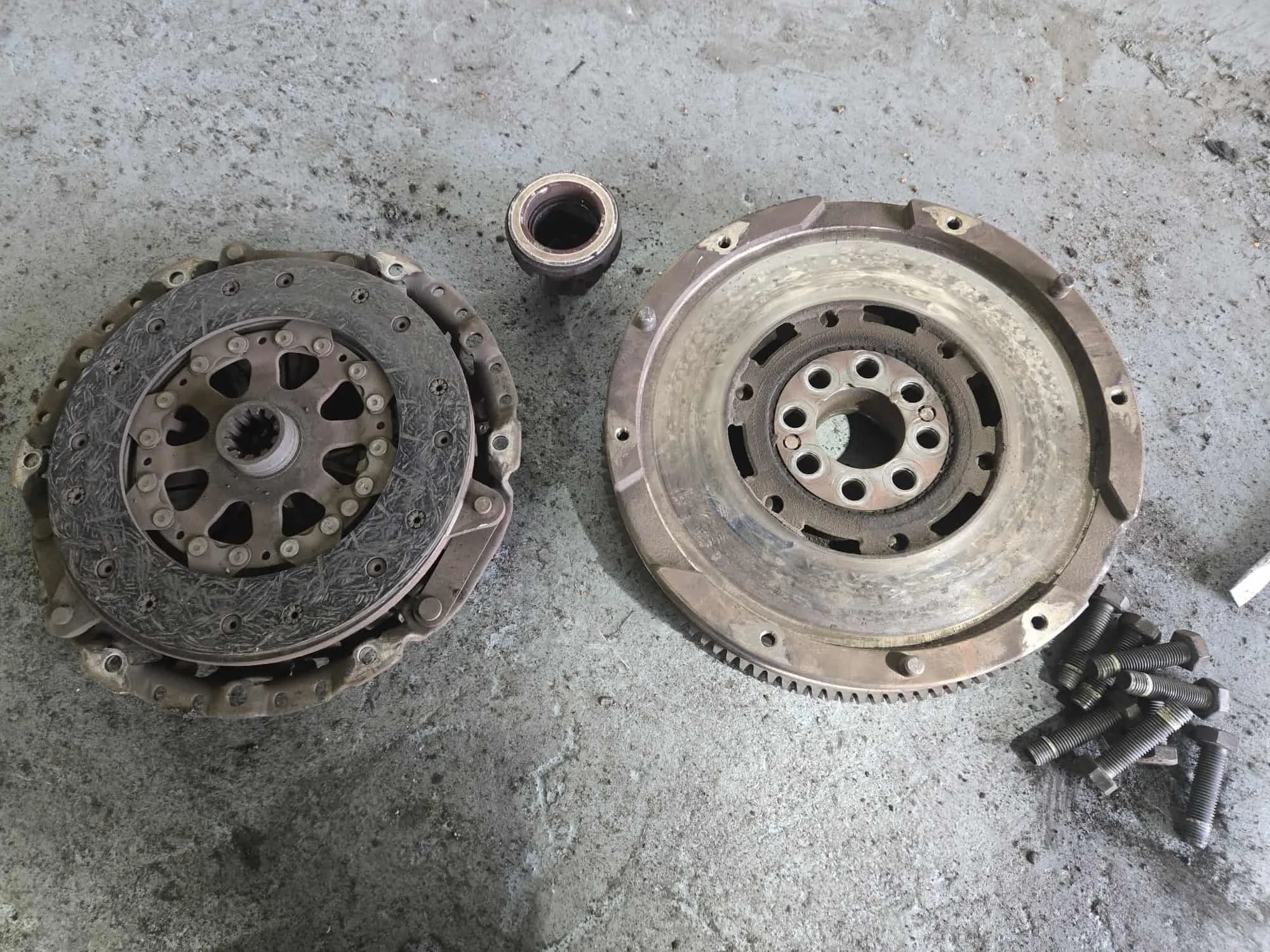 A new dual mass flywheel and clutch kit for a BMW E90 laid out on a workbench ready for installation.