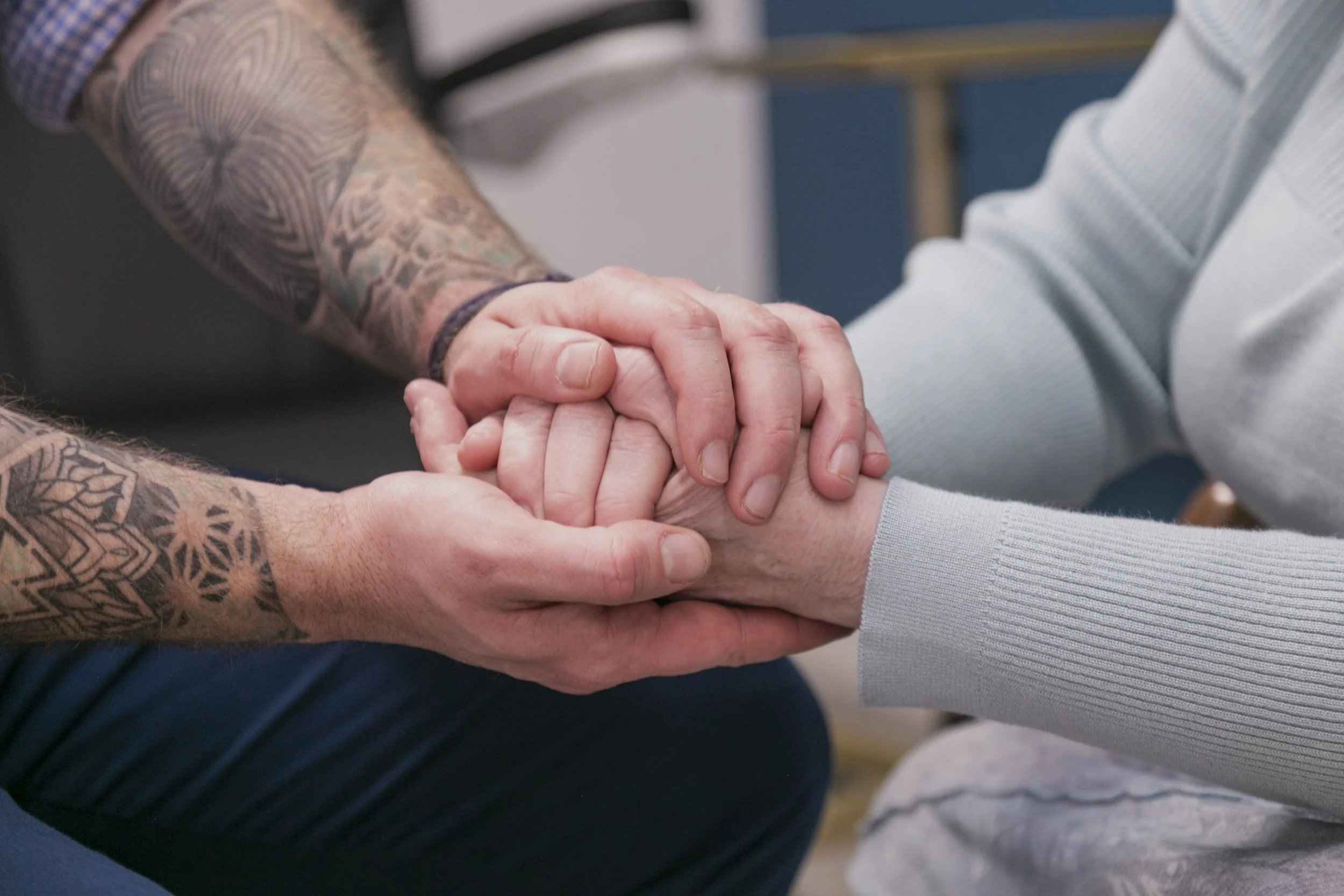 Silhouette of a human head with tangled multicolored threads being handled by four black-and-white hands in a digital illustration.