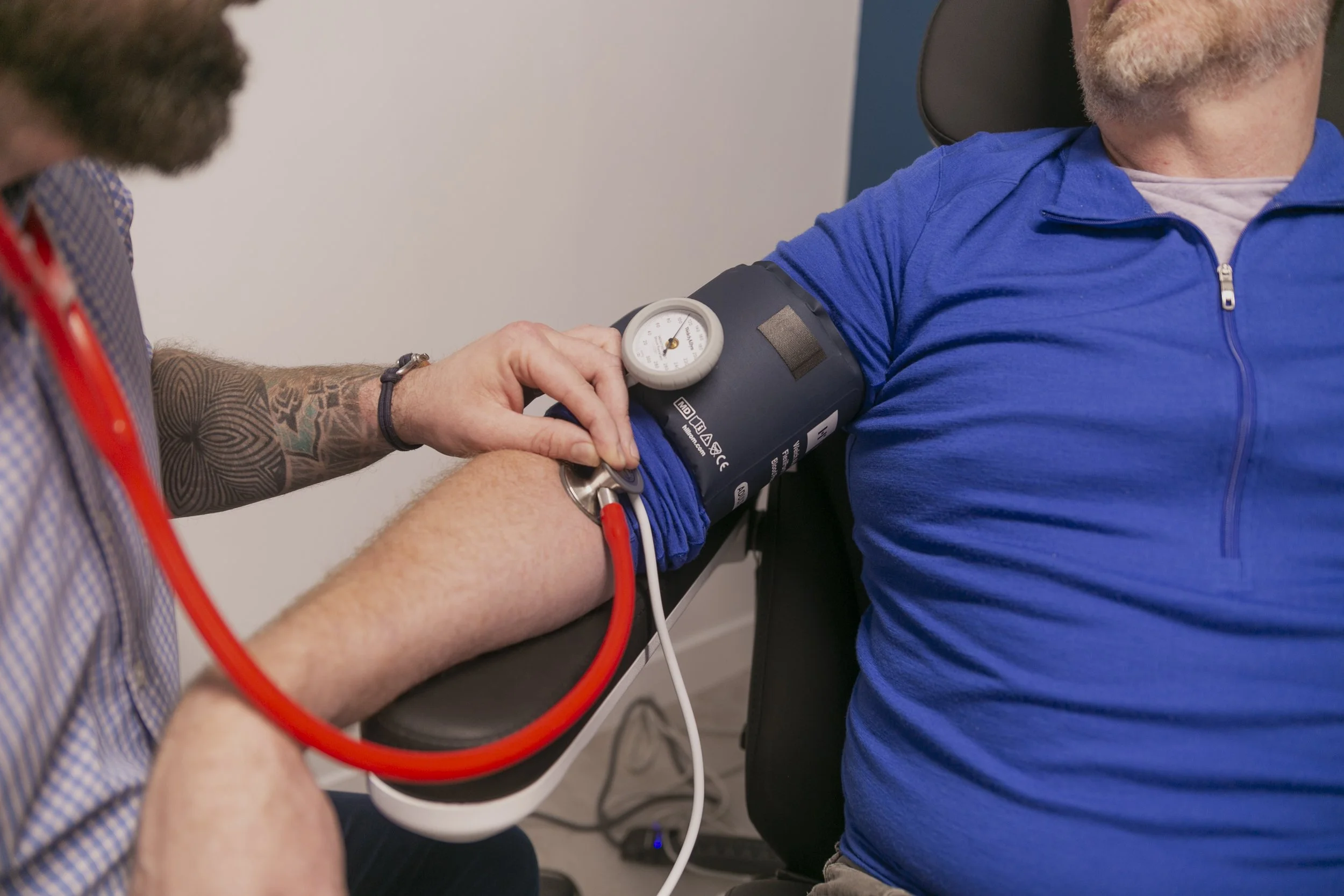 Primary care clinician checking an adult patient’s blood pressure during a routine medical visit.