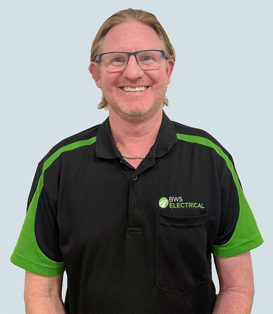 A smiling man with glasses and blonde hair, wearing a black and green polo shirt with the logo 'BWS Electrical'.