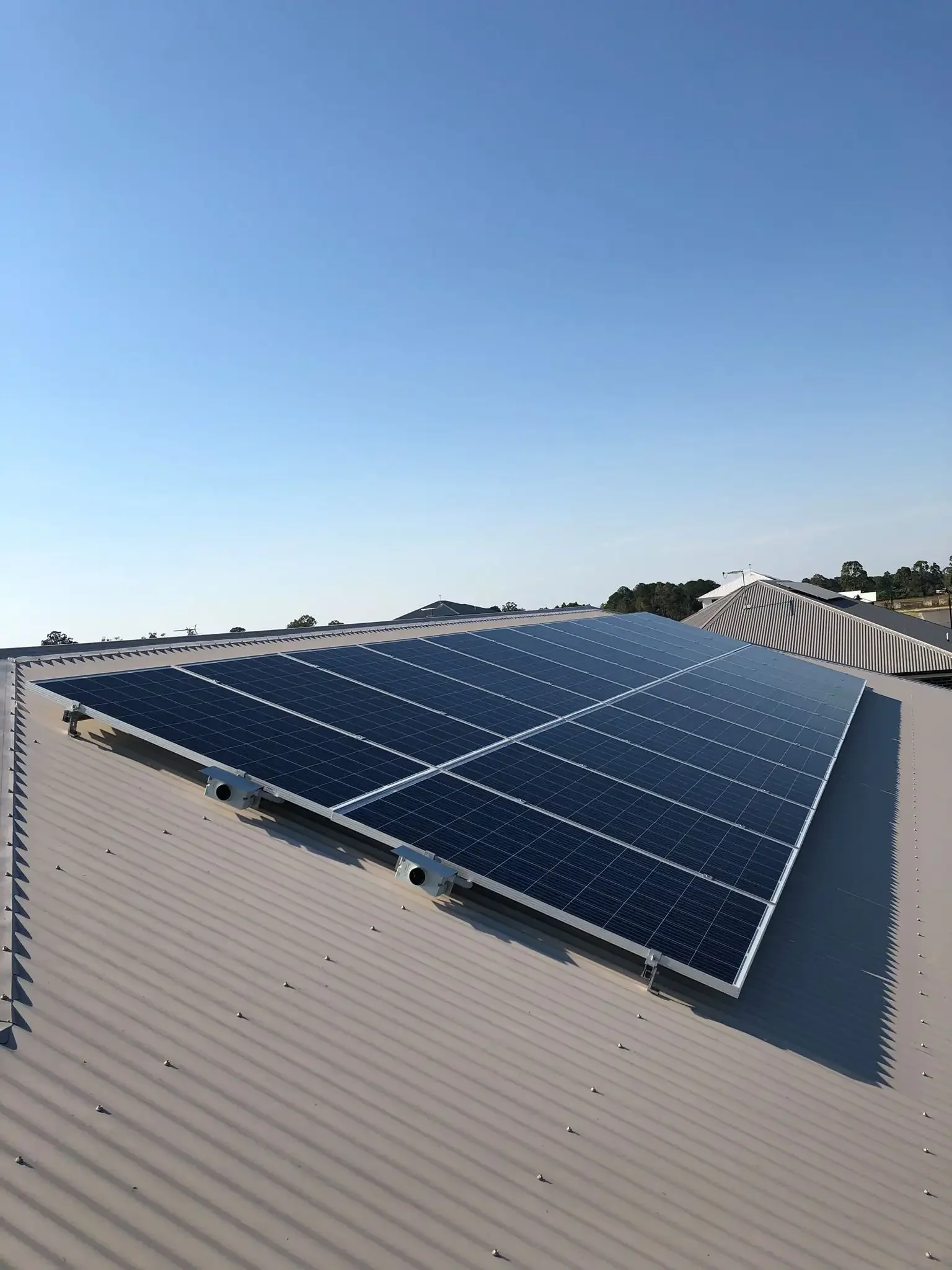 Solar panels installed on a metal roof under a clear blue sky.
