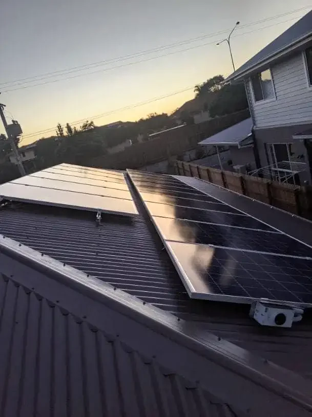 Solar panels installed on the roof of a house at sunset.