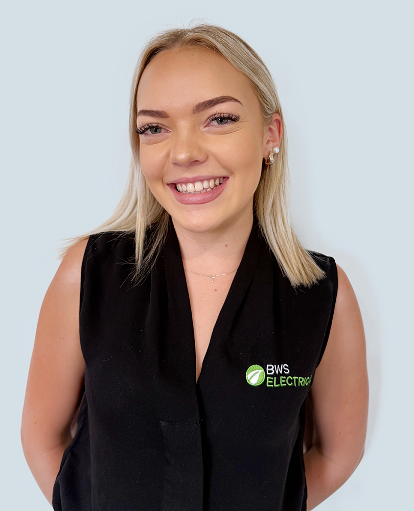 A smiling woman with blonde hair, wearing a black sleeveless vest with the logo 'BWS Electric' on it, standing against a plain light background.