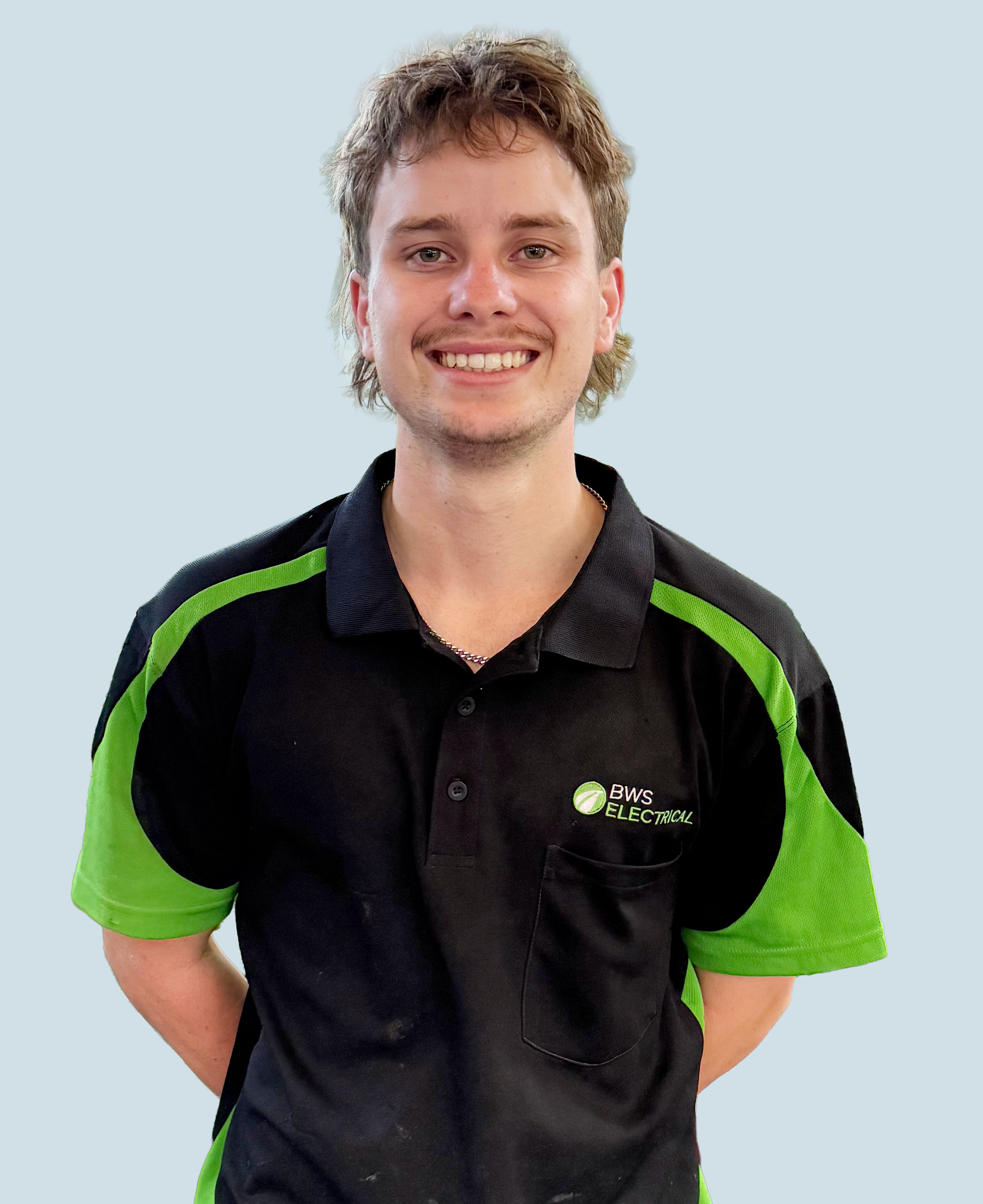 Young man smiling wearing a black and green polo shirt with 'BWS Electrical' logo, standing against a light blue background.