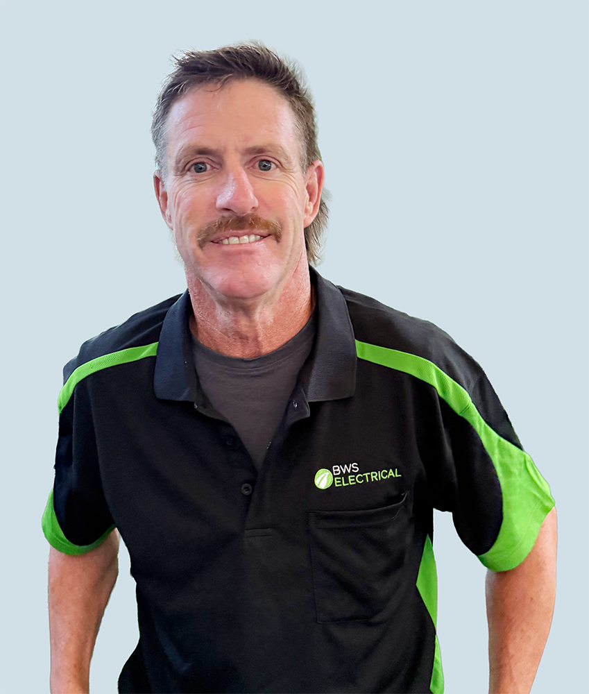 A man in a black and green BWS Electrical uniform smiling at the camera.