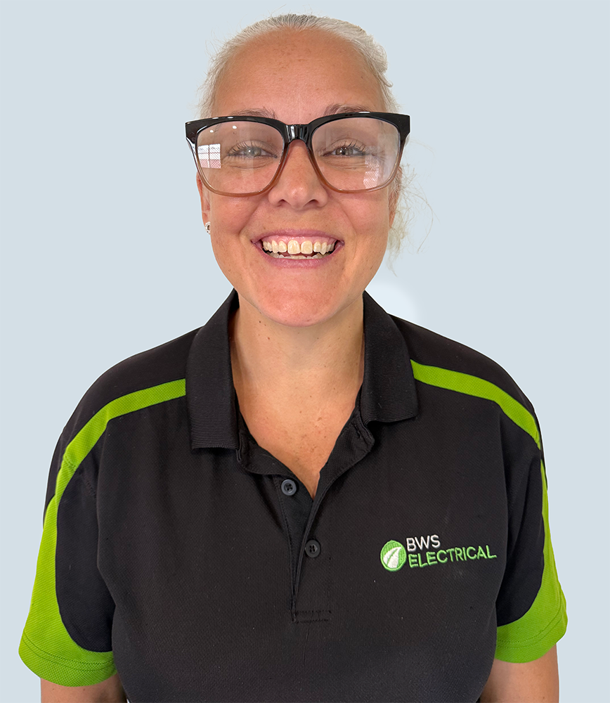 A woman with blonde hair pulled back, wearing black glasses and a black and green collared polo shirt with the logo 'BWS Electrical'.