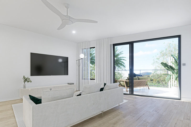 Modern living room with white walls and furniture, a large flat-screen TV, a ceiling fan, and sliding glass doors opening to an outdoor balcony with seating and views of trees and sky.