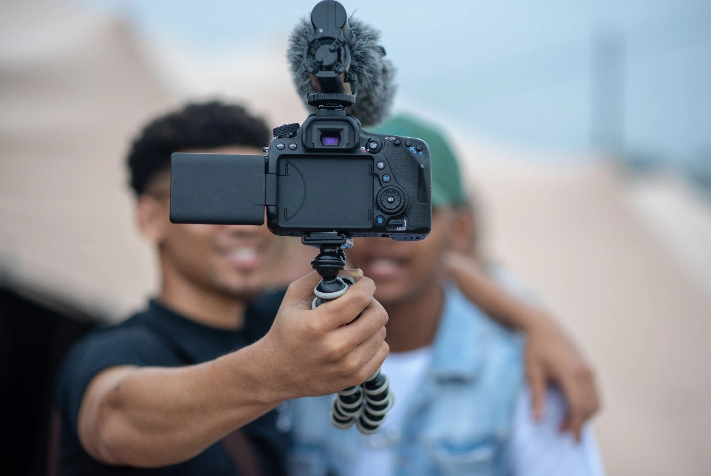Hand holding a professional camera with a shotgun mic, representing seamless influencer coordination and quality content creation by talent.