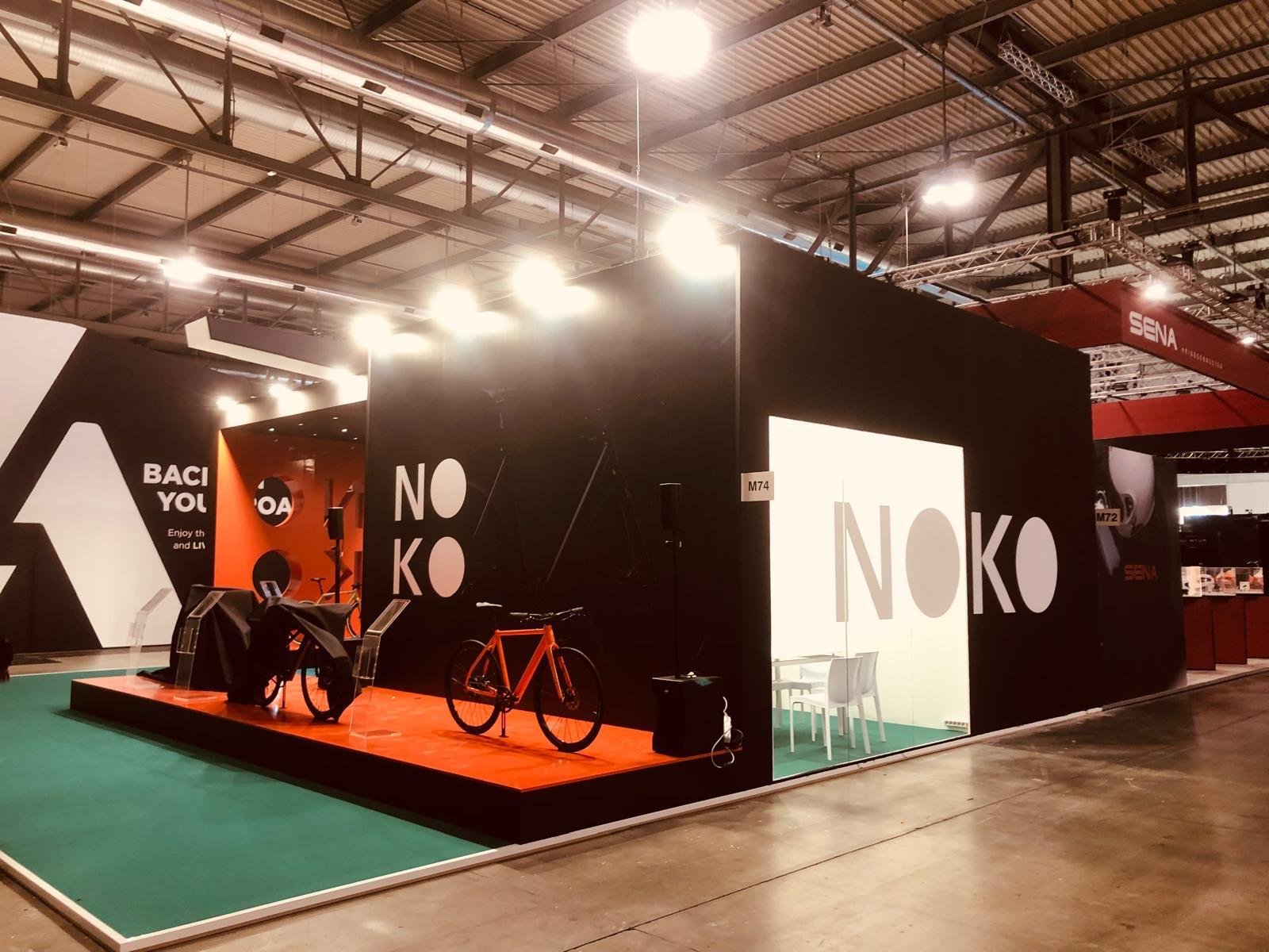 Stand di un'esposizione alla fiera con dito pannelli pubblicitari neri e bianchi, biciclette e attrezzature sportive.