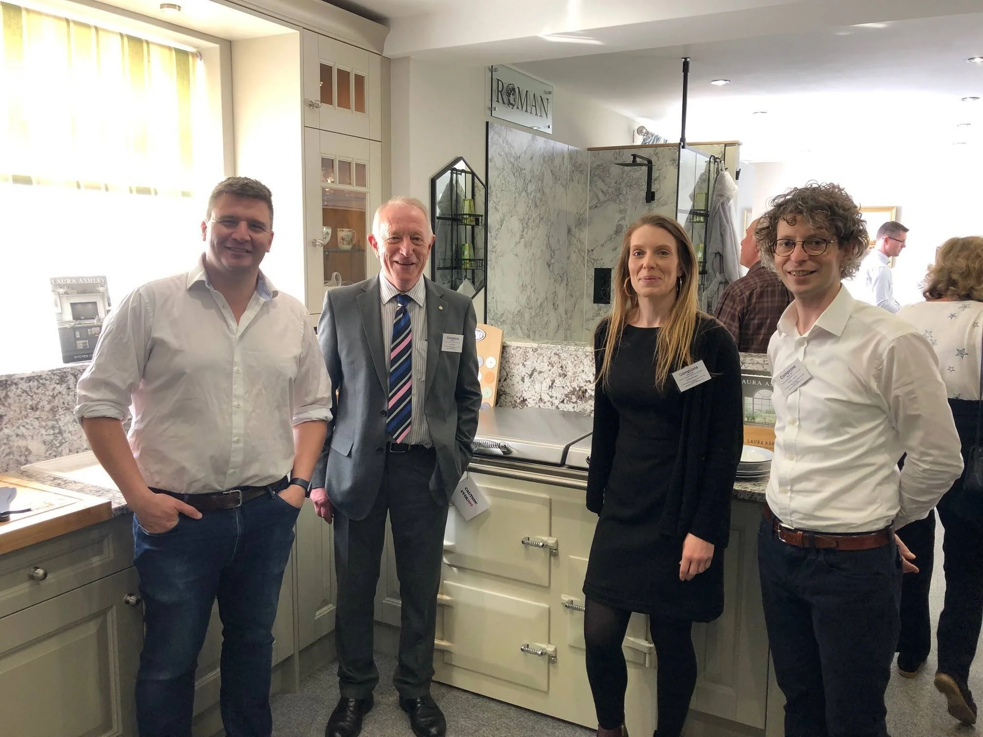 Four people standing together in a kitchen display at an event, smiling and posing for the photo.