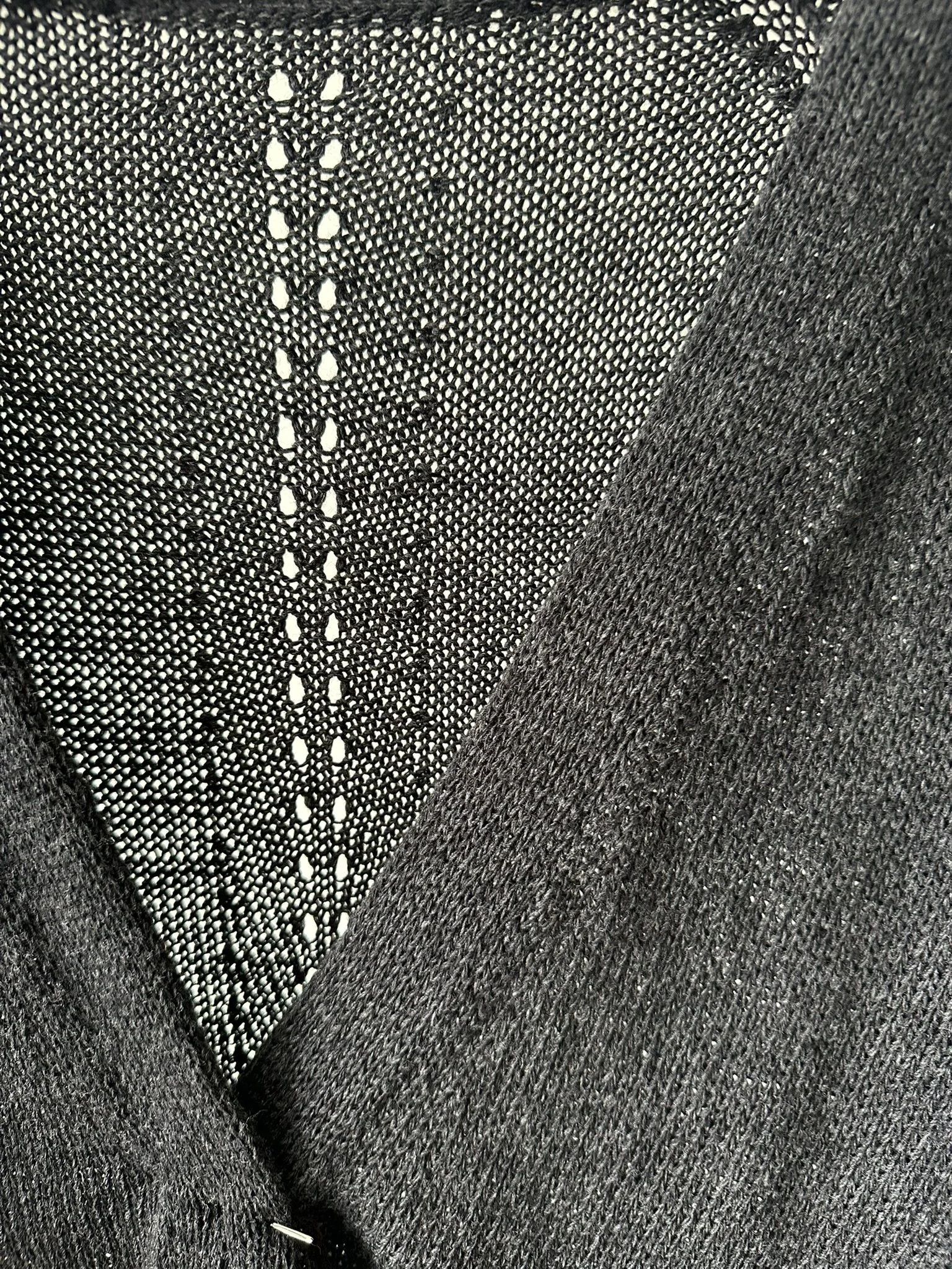 Close-up of a black mesh fabric with a diagonal seam, showing detailed texture and small holes.