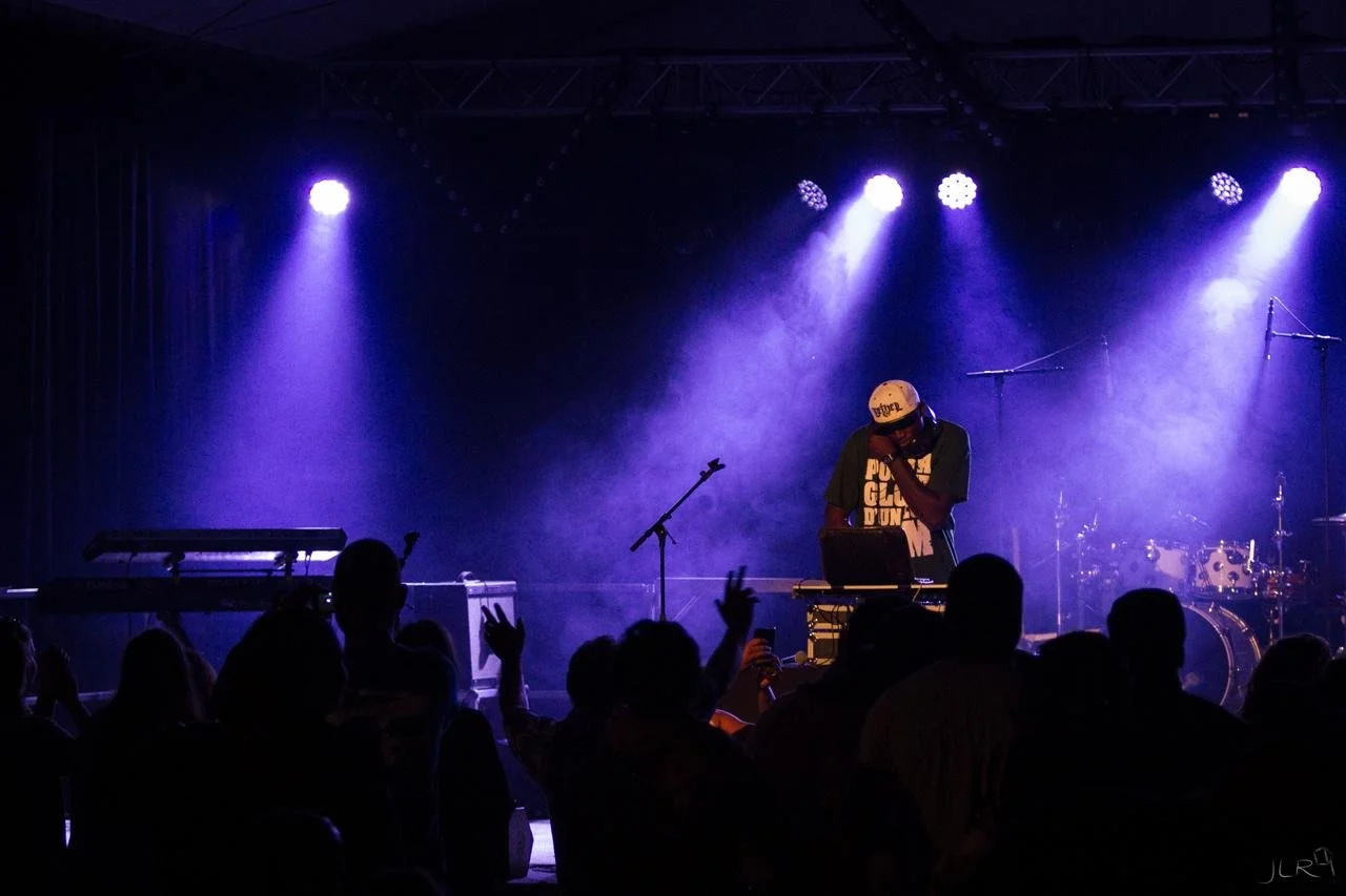 Un DJ sur scène avec des lumières bleues et une foule devant