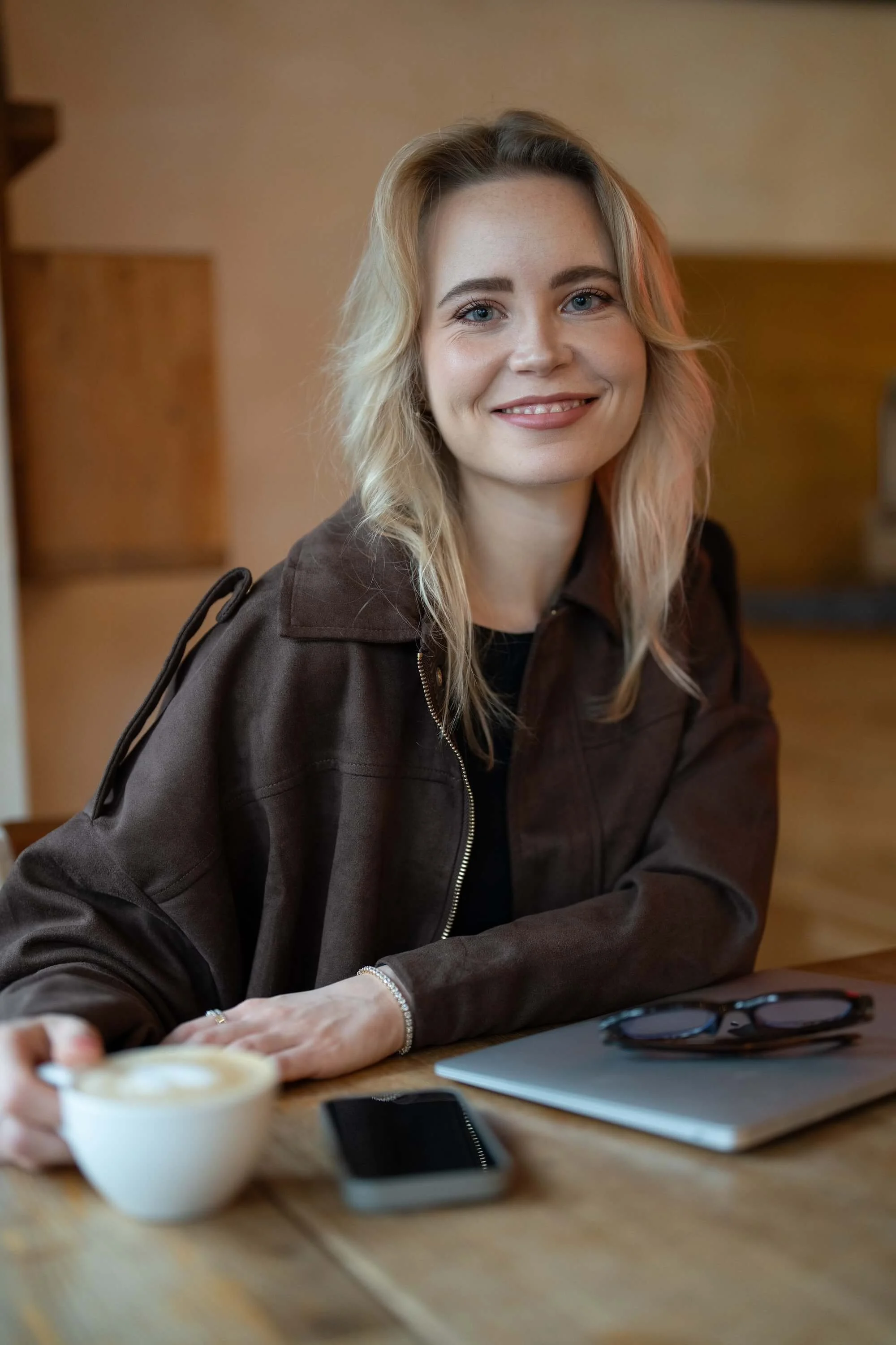 Webdesignerin Lena Brückner von Sitewise Webdesign sitzt lächelnd mit Laptop und Smartphone im Café | Squarespace Webdesign Frankfurt