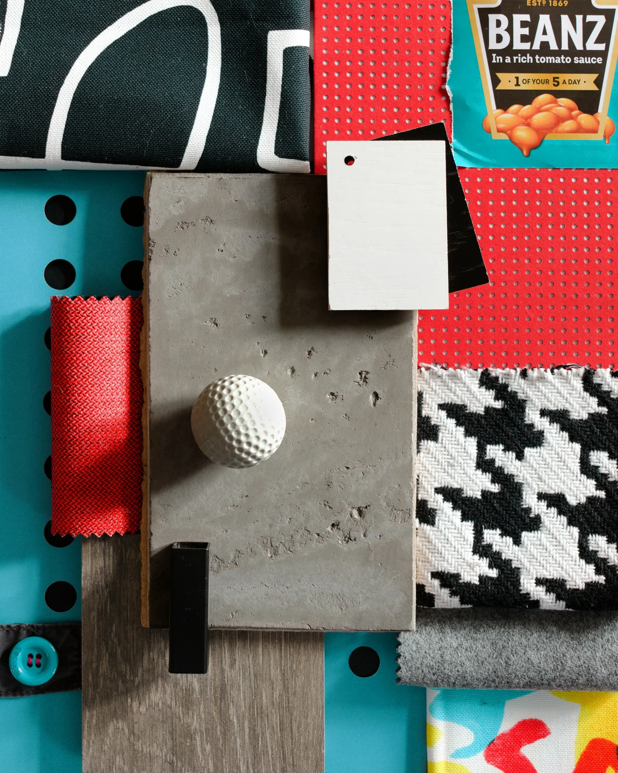 Un collage di materiali vari, tra cui un pezzo di cemento, tessuti (pied de poule bianco e nero, rosso, grigio), un frammento di legno, una palla da golf bianca e una scatola di Heinz Beanz in alto a destra, su uno sfondo blu perforato.