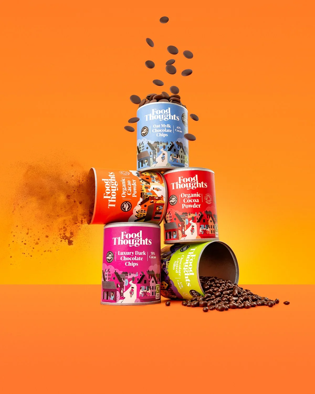 Four colorful cans of Food Thoughts chocolate products stacked in a pyramid against an orange background, with some chocolate chips spilling out of an open can and falling from above.