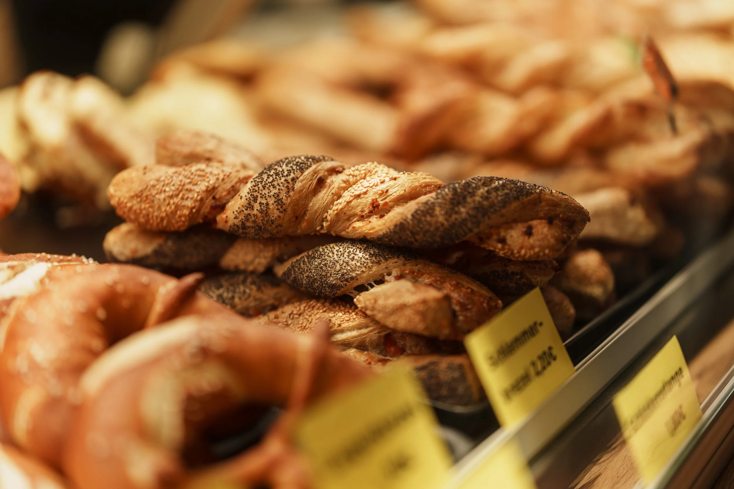 Verschiedene Paskalien, Brote und Brötchen in einer Bäckerei-Auslage, einige mit Sesam und Mohn bedeckt.