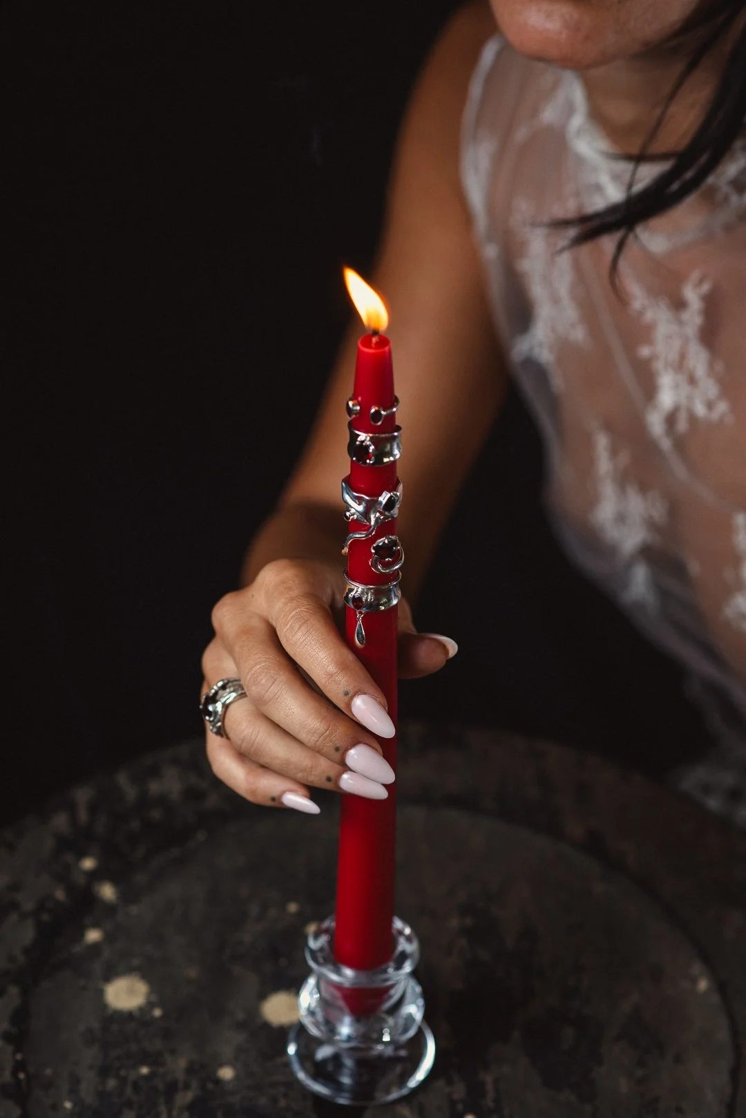 Una mujer sostiene una vela roja, luz cálida sobre la piel: una escena que simboliza transformación, inicio y renacimiento.