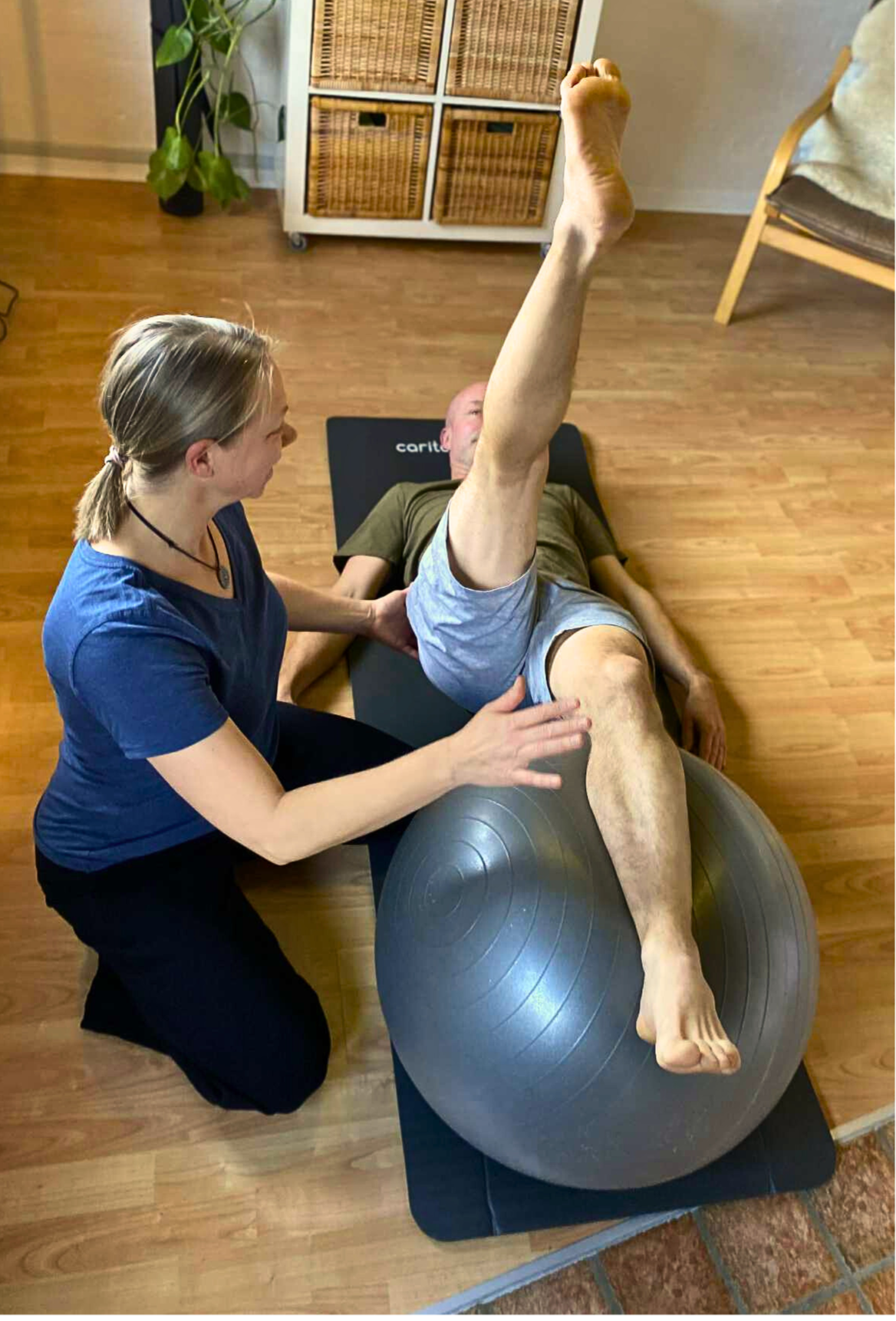 Stabilitetstræning med brug af træningsbold. Fysioterapeut guider patienten i at lave øvelsen rigtigt.