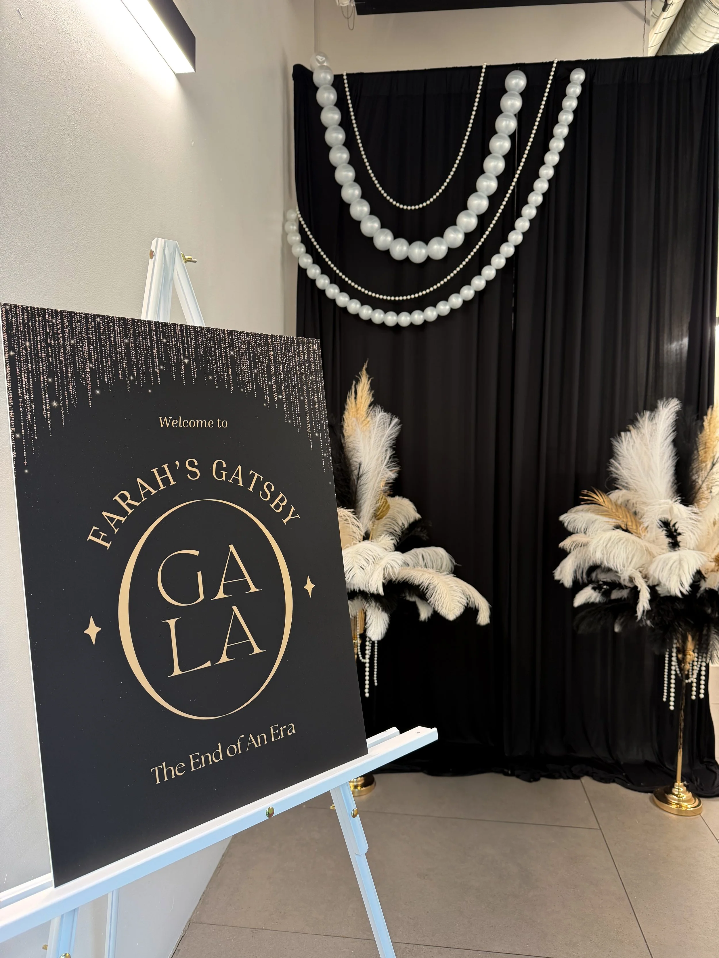 welcome sign, pearls, feathers and black drape backdrop